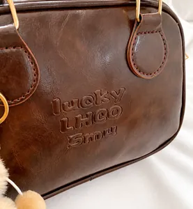 Detail of retro dark brown leather handbag featuring golden hardware and embossed logo