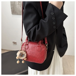 Detail of red leather mini bag with lucky letter embossing and cute plush lion charm