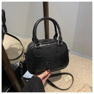 Detail of a black retro square bag with embossed lettering and golden hardware accents