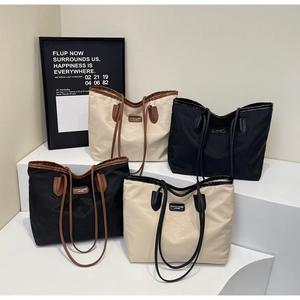 Close-up of stylish large tote bags with leather straps displayed on minimalist white stands