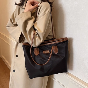 Minimalist large-capacity black tote bag with brown trim and shoulder straps for commuting