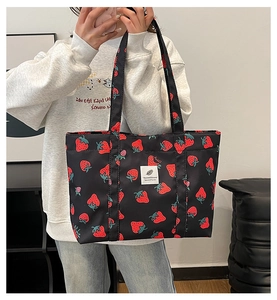 Close-up of strawberry print tote bag with realistic fruit patterns and logo detail