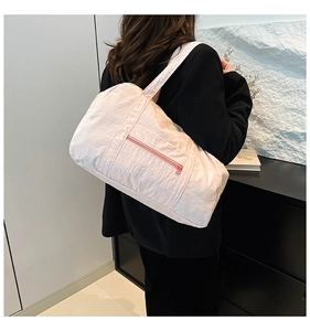 Vue détaillée d'un grand sac bandoulière en nylon rose clair porté par un mannequin