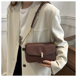 Detail einer dunkelbraunen matten Lederschultertasche mit goldener Hardware und Kette