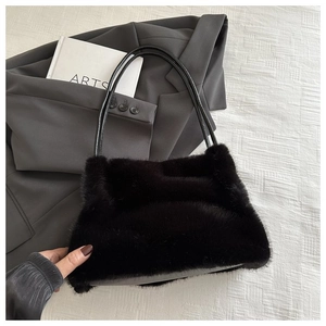Close-up of black faux fur shoulder bag texture with slim leather strap on a minimalist setup