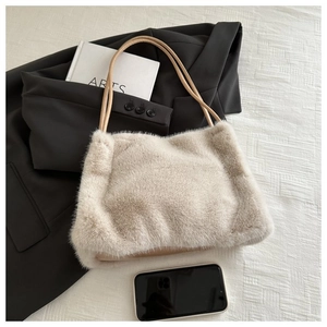 Close-up of beige plush tote bag with slim faux leather handles on a flat lay background