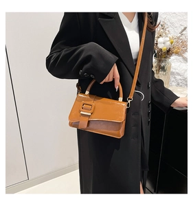 Brown glossy leather crossbody bag styled with a black blazer in a lifestyle setting