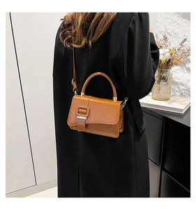 Brown leather crossbody bag worn by model in a minimalist interior setting