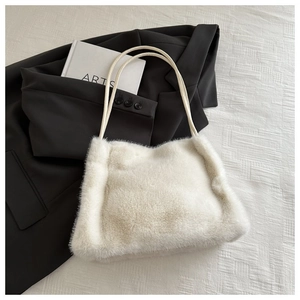 Close-up of soft off-white faux fur shoulder bag with slender twin handles and plush texture