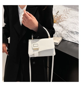 Close-up of white PU leather handbag with a large square buckle and gold metal hardware
