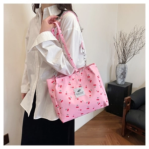 Detailed view of pink cherry print tote bag with chain strap and cloth patch accents