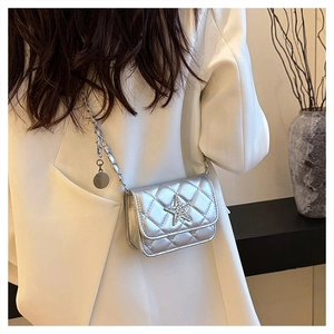 Détail d'un sac bandoulière argenté matelassé avec boucle étoile en cristal et chaîne