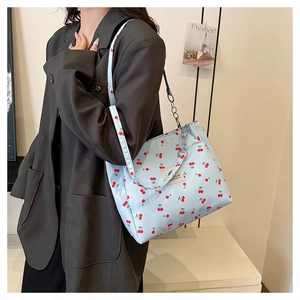 Detail of light blue cherry print tote bag with silver chain strap and vintage label