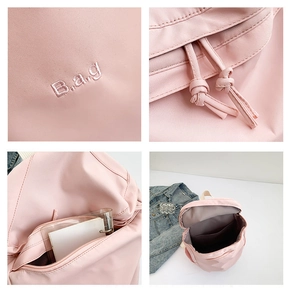 Detalle de mochila de nailon rosa con cierre de cordón, bolsillos internos y bordado fino