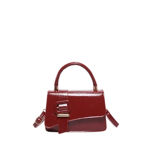 Glossy burgundy leather satchel with golden buckle and adjustable strap on white background