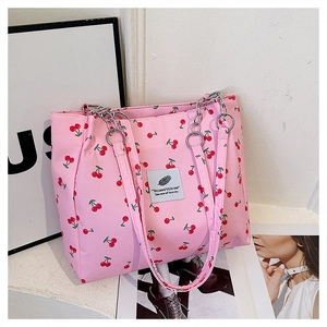 Detail of pink cherry print tote bag with stylish blue woven patch and silver ring metal hardware