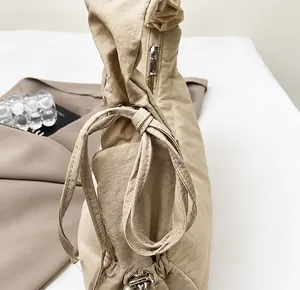 Detalle de la correa fruncida con lazo decorativo en el bolso de hombro caqui