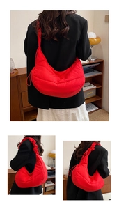 Detalle del bolso rojo acolchado con correa plisada y diseño moderno en forma de luna
