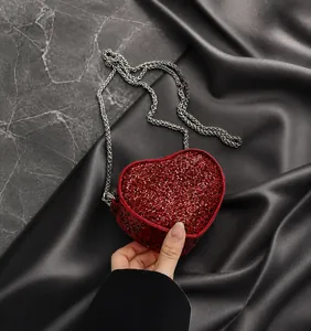 Detail of red heart-shaped sequin bag with silver chain strap and shiny glitter finish