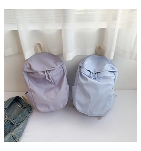 Detalle de las mochilas de nailon lavanda y azul claro con el bordado B.a.g en el frontal