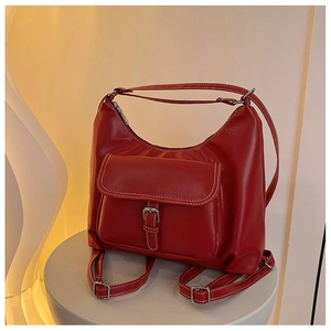 Gros plan du sac en cuir rouge montrant les coutures contrastées et la boucle argentée