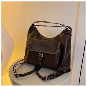 Détail du sac hobo marron foncé avec coutures contrastées blanches et boucle en métal argenté