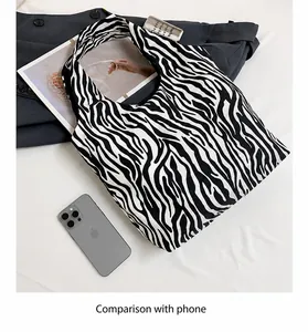 Gedetailleerde groottevergelijking van zebra print emmertas met een mobiele telefoon
