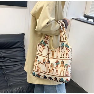 Close-up of printed canvas bucket bag featuring ancient Egyptian gods worn with a trench coat