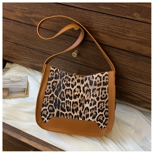 Close-up of leopard print saddle bag on white fabric background in wooden drawer