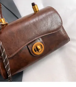 Detail of dark brown oil-wax leather texture and brass twist lock on commuter bag
