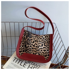Detail of red leather and leopard print patchwork shoulder bag on a metal stand