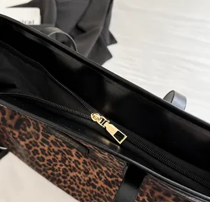 Detail des glatten Metallreißverschlusses und Goldlogos auf der Leopard-Tasche