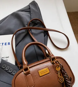 Detail der dunkelbraunen Vintage Bowling-Tasche mit goldenem Logo und Seitenanhänger