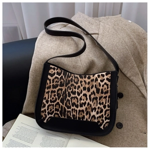 Close-up of leopard print handbag with black faux leather trim on an aesthetic background