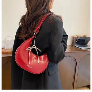 Detail of red crescent underarm bag with Fashion lettering and pearl bow charm