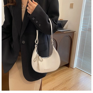 White crescent underarm bag with pearl bow charm and minimalist textured faux leather