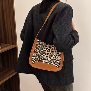 Retro leopard print crossbody bag with brown leather trim shown on a model in a cozy room