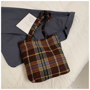 Detail der braunen Vintage-Karo-Tragetasche aus Wolle mit Tweed-Struktur auf weißem Stoff