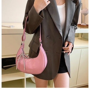 Detail of pink hobo bag with beaded bow pendant and Fashion print worn over a brown blazer