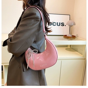 Pink semi-circle shoulder bag with glossy finish and pearl bow charm detail