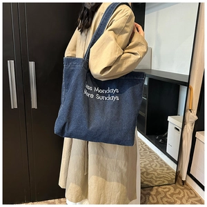 Dettaglio della borsa tote in denim blu con ricamo bianco 'Less Mondays More Sundays'