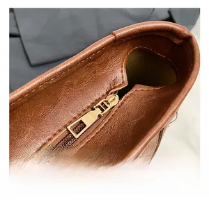 Close-up of golden metal zipper and stitching detail on dark brown leather tote bag