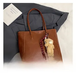 Brown vintage faux leather tote bag detail with cute plush bear charm and soft texture