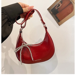 Detail of red patent leather hobo bag with fashion text and silver bow charm