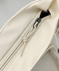 Dettaglio della cerniera in metallo sulla borsa a tracolla in tela bianca da donna