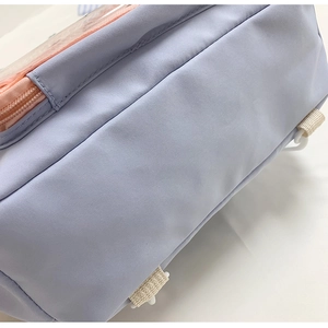 Dettaglio borsa in nylon lilla con cerniera rosa e cinghie regolabili color bianco crema