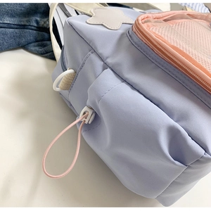 Dettaglio borsa blu in nylon con tasca a rete arancione, toppa a stella e gancio a D