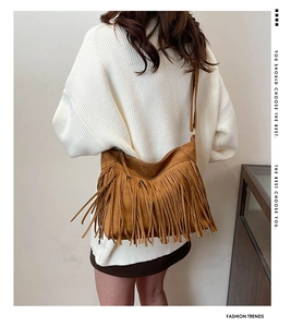 Detailed view of brown suede crossbody bag with long tassels and thin leather strap