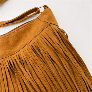 Close-up of brown suede bag featuring dense fringe tassels and gold hardware accents