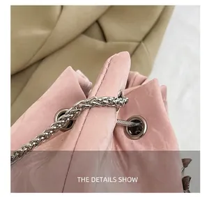 Detailopname van roze emmertas met zilveren metalen ketting en verfijnde stikseldetails